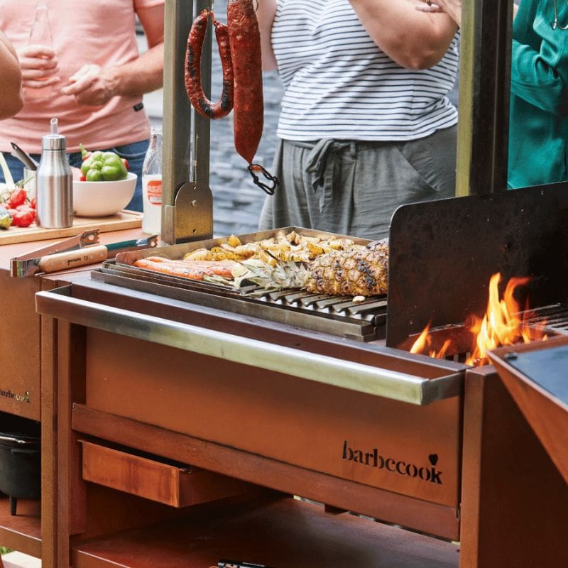 Barbecue grill with food being cooked, people in the background