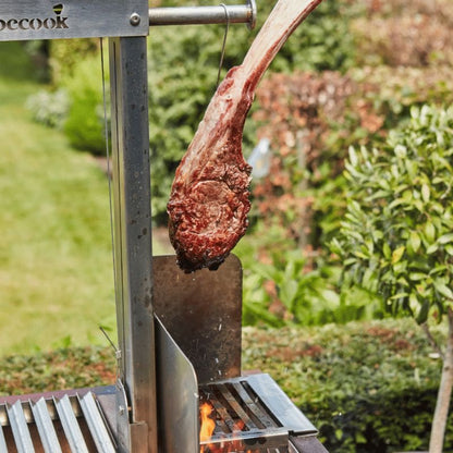 Grilled steak on a metal skewer over a grill with a garden background